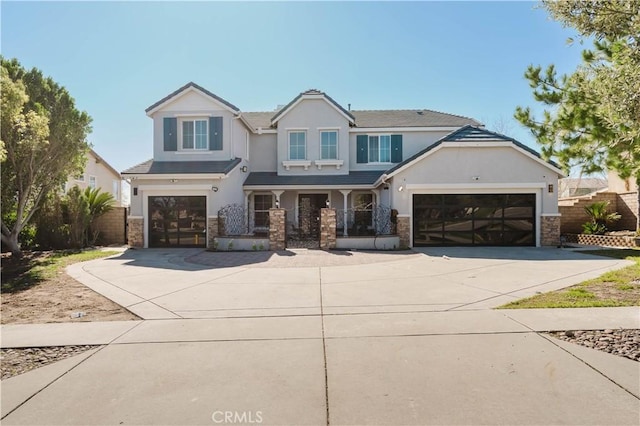 view of front facade with concrete driveway, stone siding, fence, and stucco siding