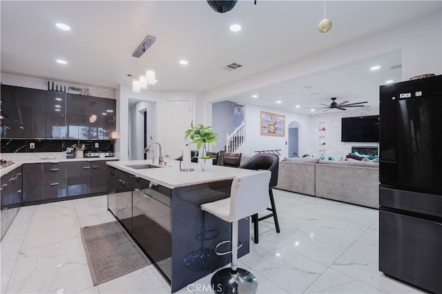 kitchen with arched walkways, marble finish floor, freestanding refrigerator, a sink, and modern cabinets