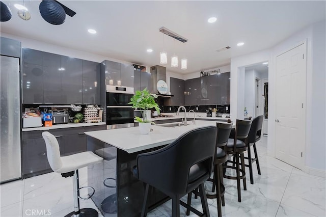 kitchen with modern cabinets, marble finish floor, wall chimney range hood, pendant lighting, and a sink