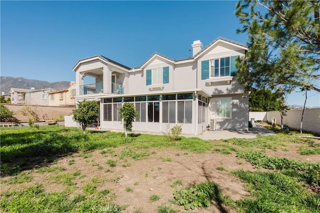 back of property with fence, a chimney, stucco siding, and a sunroom