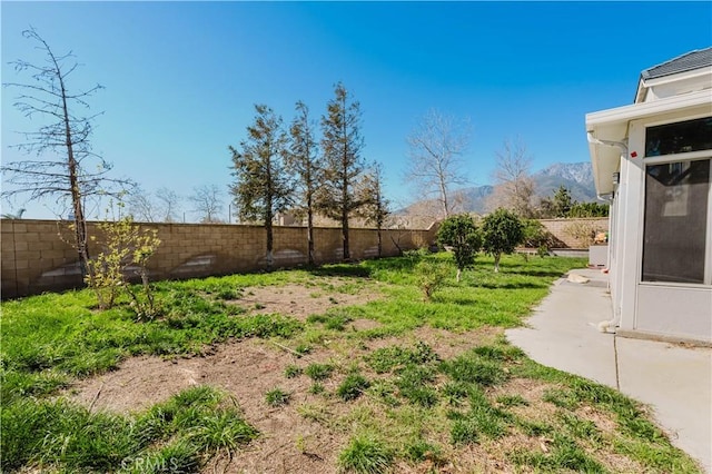 view of yard featuring a patio, a fenced backyard, and a mountain view