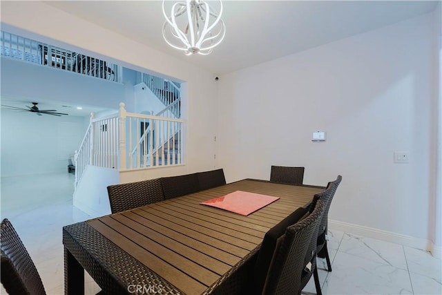 dining area featuring marble finish floor, stairs, baseboards, and ceiling fan with notable chandelier