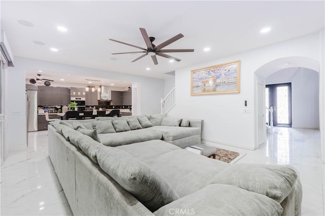 living area with arched walkways, ceiling fan, recessed lighting, stairs, and marble finish floor