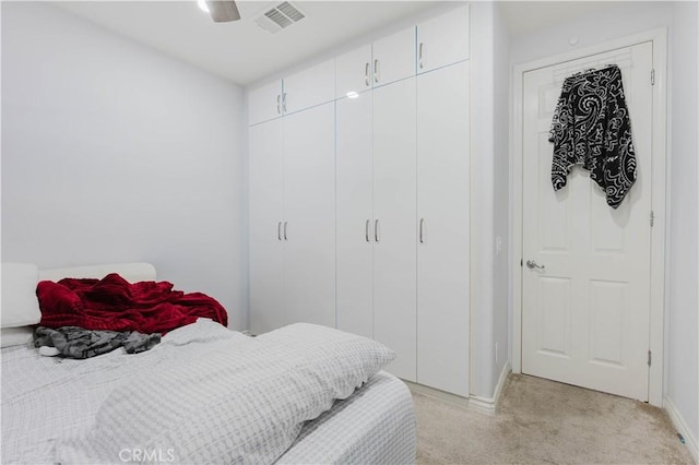 bedroom featuring ceiling fan, visible vents, a closet, and light colored carpet