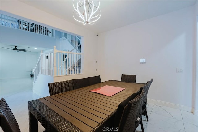 dining space featuring ceiling fan with notable chandelier, marble finish floor, stairway, and baseboards