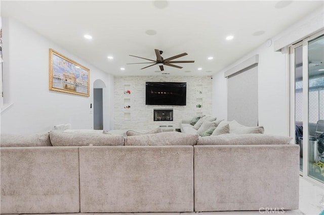living area featuring recessed lighting, a fireplace, a ceiling fan, marble finish floor, and arched walkways