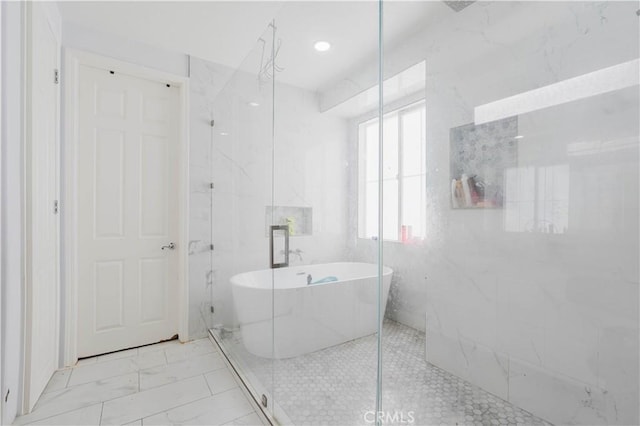 bathroom featuring tile walls, a freestanding tub, marble finish floor, and a marble finish shower