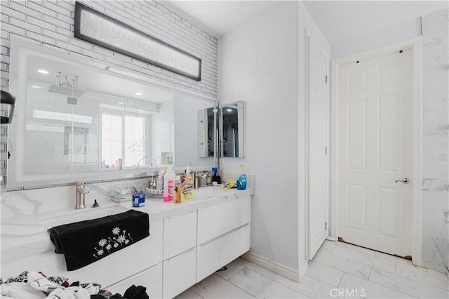 bathroom featuring a stall shower, marble finish floor, baseboards, and double vanity