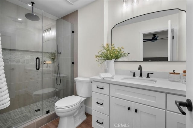 bathroom featuring toilet, a stall shower, wood finished floors, and vanity