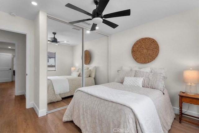 bedroom with ceiling fan, a closet, wood finished floors, and visible vents