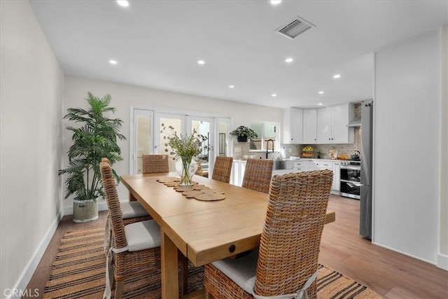 dining room with french doors, light wood-type flooring, visible vents, and recessed lighting