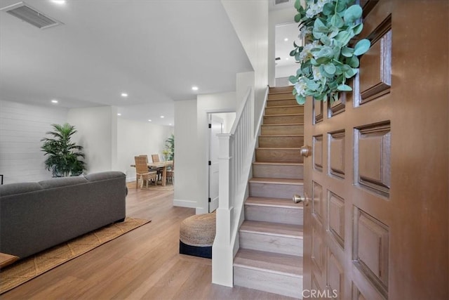 stairway featuring baseboards, visible vents, wood finished floors, and recessed lighting