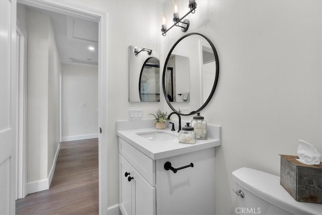 bathroom featuring toilet, baseboards, wood finished floors, and vanity