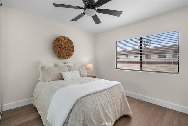 bedroom with a ceiling fan, baseboards, and wood finished floors