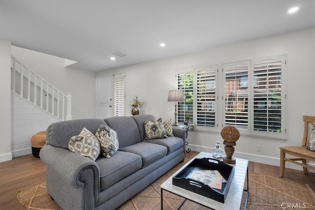 living area featuring baseboards, stairway, wood finished floors, and recessed lighting