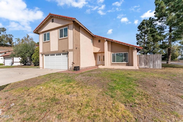 view of front of home with stucco siding, concrete driveway, fence, a garage, and a front lawn