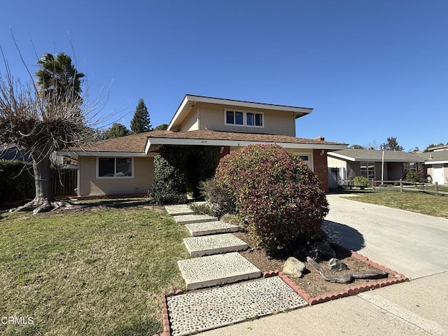 view of front facade featuring concrete driveway, fence, a front lawn, and stucco siding