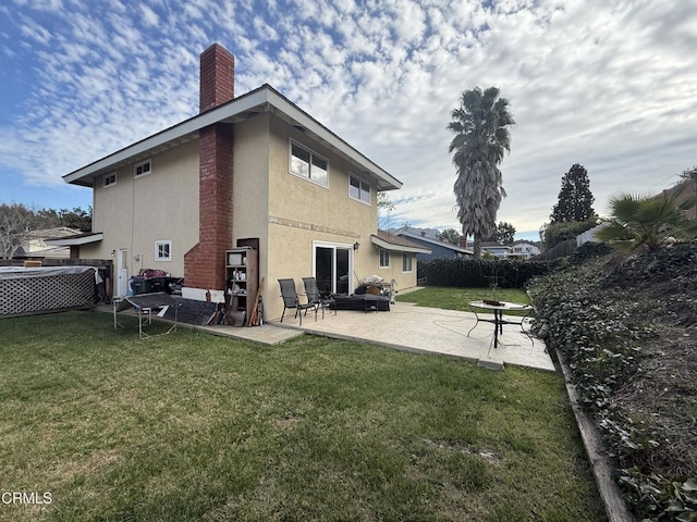rear view of house featuring a patio, a yard, fence, and stucco siding