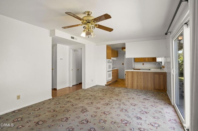 205 Bluefield Ave, Newbury Park, CA 91320 - kitchen with brown cabinetry, light carpet, ceiling fan, light countertops, and a peninsula