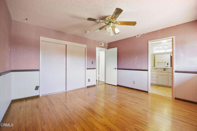 205 Bluefield Ave, Newbury Park, CA 91320 - unfurnished bedroom with wood finished floors, wainscoting, a closet, a textured ceiling, and connected bathroom