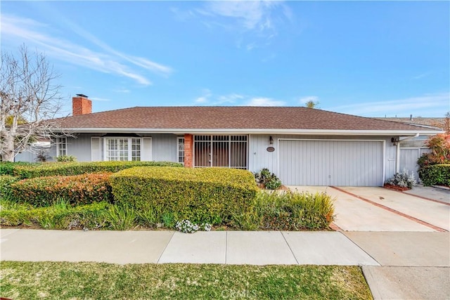 single story home featuring concrete driveway, a chimney, and a garage