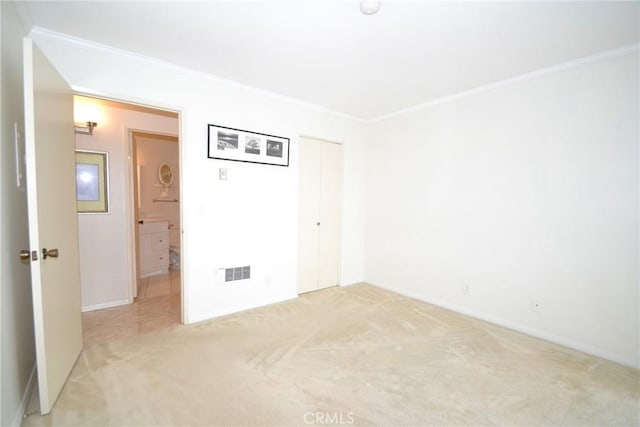 spare room with light colored carpet, crown molding, and visible vents