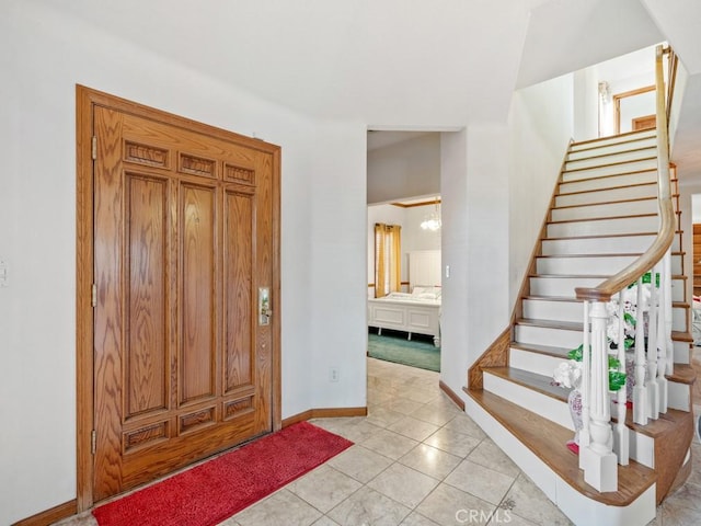 entrance foyer featuring baseboards, stairway, and light tile patterned flooring