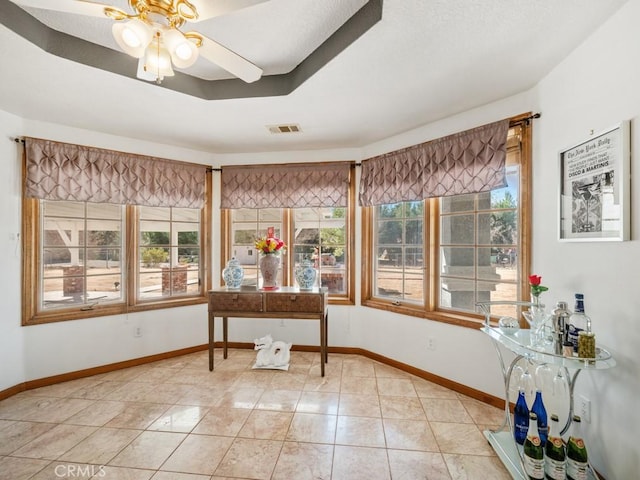 sunroom / solarium featuring ceiling fan, a tray ceiling, and visible vents