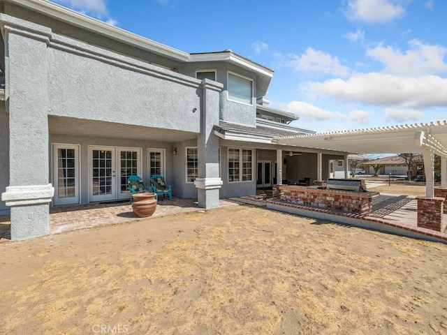 rear view of house featuring a patio, french doors, stucco siding, and a pergola