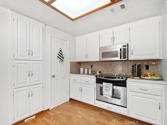 kitchen featuring light wood-type flooring, visible vents, appliances with stainless steel finishes, and white cabinets