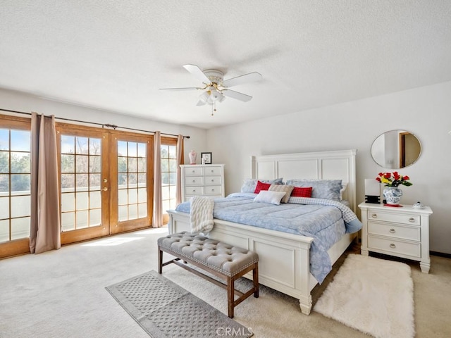 bedroom with access to exterior, french doors, light colored carpet, and a textured ceiling