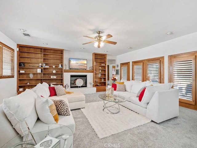 living area featuring a ceiling fan, carpet, a fireplace, and plenty of natural light