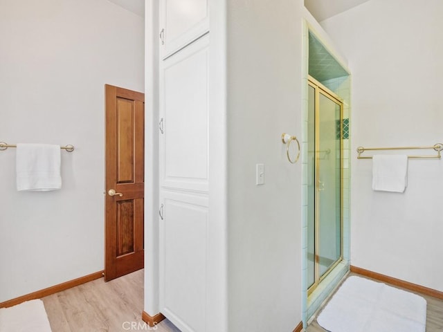 full bath with baseboards, wood finished floors, and a shower stall