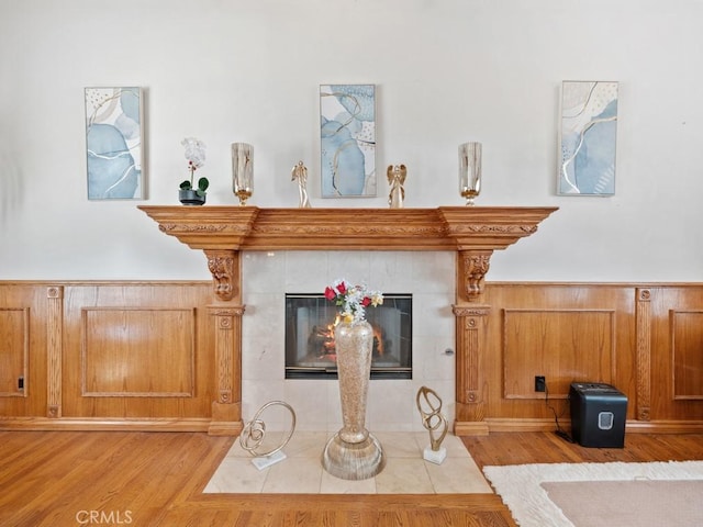 details featuring wainscoting, a fireplace, wood walls, and wood finished floors