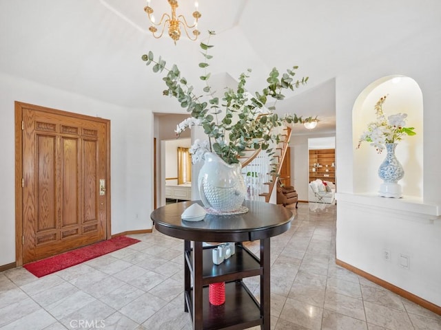 foyer featuring lofted ceiling, stairs, baseboards, and a chandelier