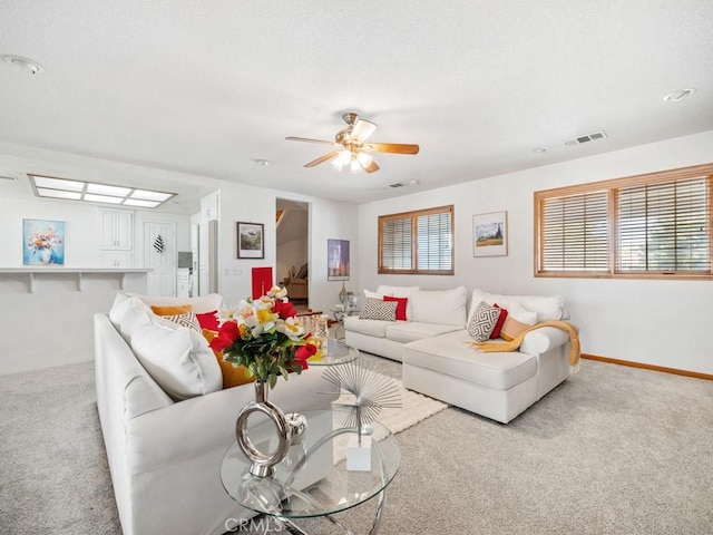 carpeted living area featuring ceiling fan, visible vents, and baseboards