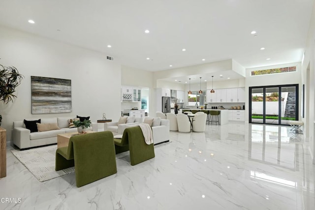 living area with visible vents, recessed lighting, and marble finish floor