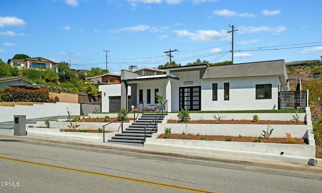 modern home featuring stairway, stucco siding, and fence