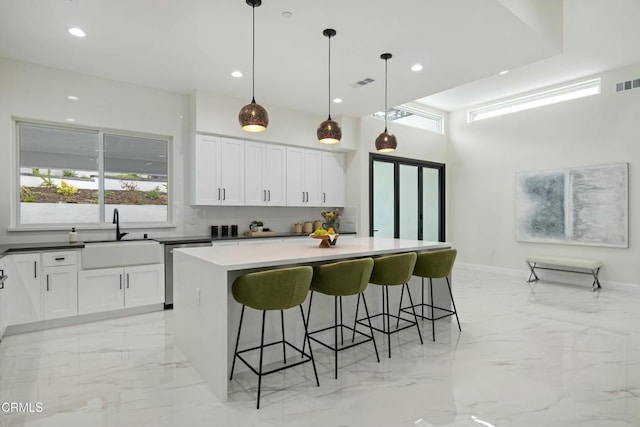 kitchen with visible vents, marble finish floor, a sink, stainless steel dishwasher, and white cabinetry