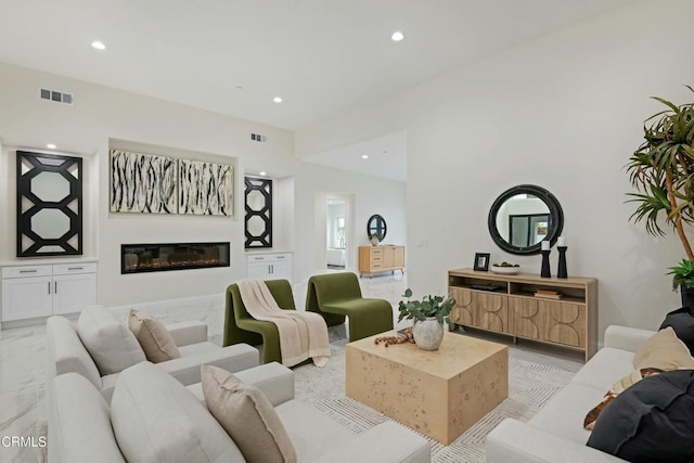 living room with a glass covered fireplace, recessed lighting, and visible vents