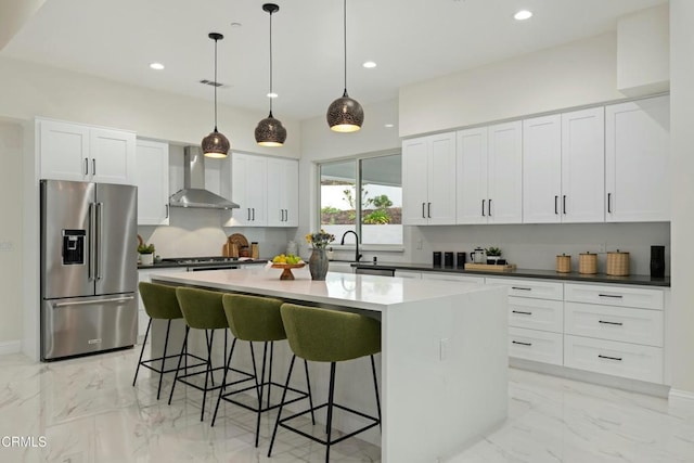 kitchen with a kitchen breakfast bar, wall chimney exhaust hood, marble finish floor, and appliances with stainless steel finishes