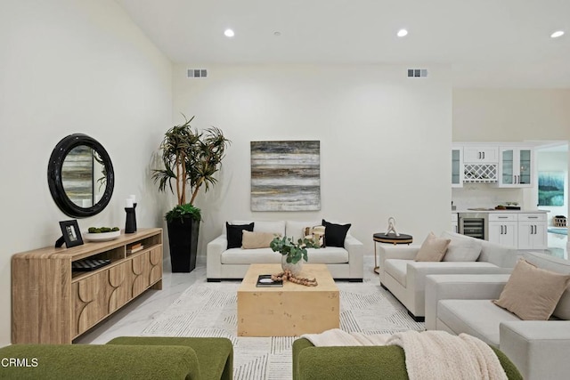 living room featuring beverage cooler, visible vents, marble finish floor, and a dry bar