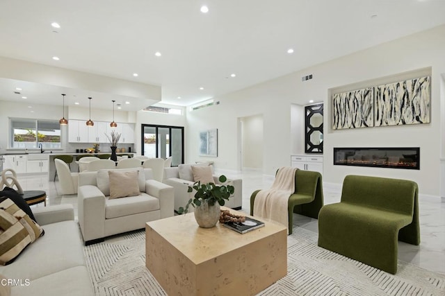 living room with visible vents, marble finish floor, a glass covered fireplace, recessed lighting, and baseboards