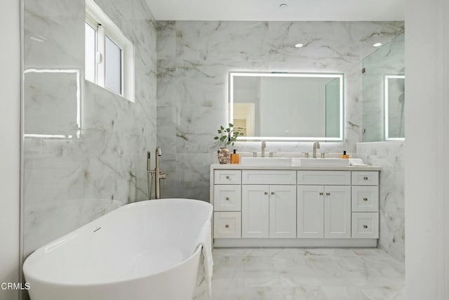 bathroom with tile walls, a freestanding bath, marble finish floor, and vanity