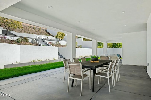 view of patio with outdoor dining area, stairs, and fence