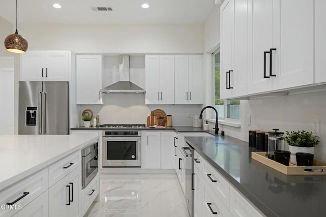 kitchen with visible vents, a sink, appliances with stainless steel finishes, wall chimney range hood, and marble finish floor