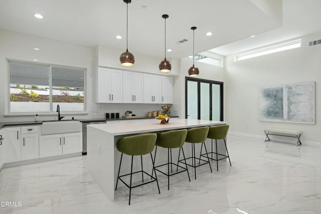 724 Via Arroyo, Ventura, CA 93003 - kitchen featuring stainless steel dishwasher, light marble finish floors, white cabinetry, a kitchen island, and a kitchen breakfast bar