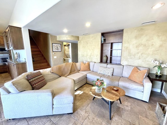 living room with stairway, stone tile flooring, visible vents, and recessed lighting