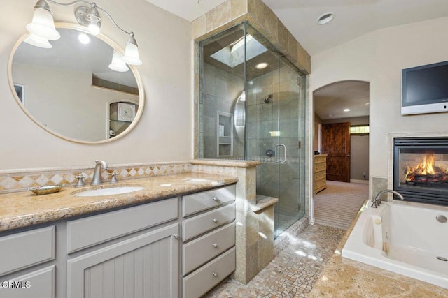 bathroom featuring a garden tub, recessed lighting, vanity, a stall shower, and a glass covered fireplace