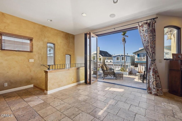 interior space featuring baseboards, stone tile flooring, and recessed lighting